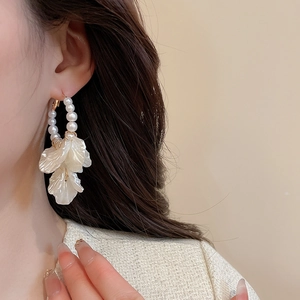 Detail view of vintage pearl drop earring with layered white petals on elegant female model