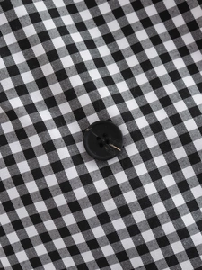 Detailed view of black and white gingham fabric texture with a matte black button