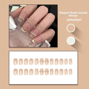 Detailed view of nude pink French tip press-on nails with rhinestone accents and full set