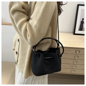 Detailed view of black bucket bag with drawstring closure being worn by a model