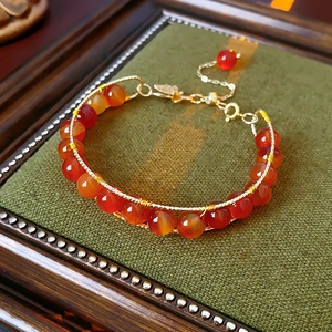 Detail of red agate bead bracelet with gold wire wrapping on a green vintage mat