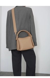 Detail view of camel leather tote bag with wide strap styled on a gray blazer