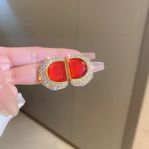 Détail de boucles d'oreilles lettre D vintage dorées avec gemmes rouges et strass