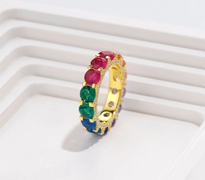 Detailed macro view of gold eternity ring with colorful gems on white background