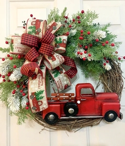 Detail of Christmas wreath featuring red truck, buffalo plaid bow, and pine branches