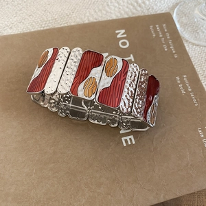Detailed view of elastic wide bracelet with reddish-brown enamel and hammered silver metal