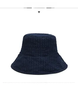 Détail d'un chapeau bob bleu marine avec tissu texturé et broderie blanche 'one'