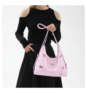 Detailed shot of a pink shoulder bag adorned with decorative silver butterflies on a white backdrop