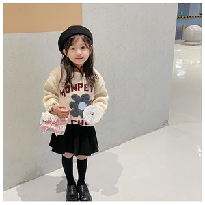 Full view of girl wearing a white knit sweater with a pink lace bow shoulder bag