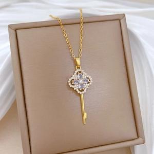 Elegant gold clover key necklace with sparkling crystals on silk background