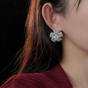 Close-up of elegant flower stud earrings with sparkling zircons on model ear