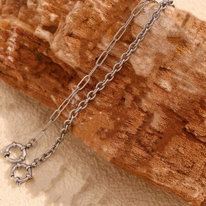 Detailed close-up of stainless steel paperclip and round link chain on rustic wood