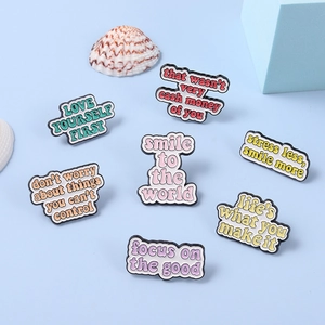 Macro view of pastel enamel pins with motivational quotes like Love Yourself and Smile