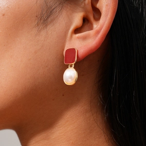 Vue détaillée d'une boucle d'oreille rouge rectangulaire et perle sur un mannequin