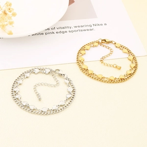 Detail of double-layer stainless steel heart charm bracelet in gold and silver finish