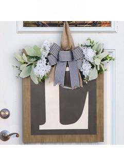 Detail of wooden welcome door sign with faux flowers and black-white striped bow decor