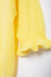 Close-up of yellow knit cardigan showing fuzzy wool texture and ruffled cuff details
