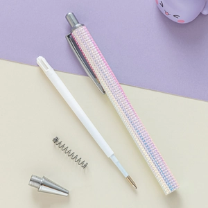 Disassembled metal ballpoint pen showing glitter barrel, silver tip, spring, and ink refill