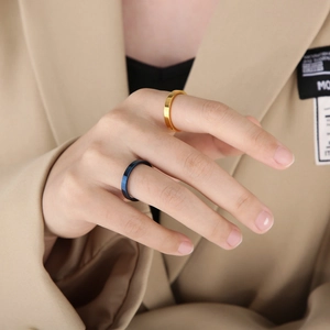 Detail of 3mm minimalist flat stainless steel rings in gold and blue on model hand