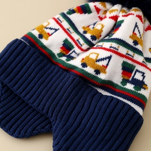 Detailed knit texture of a kid's winter hat featuring yellow excavator patterns and earflaps