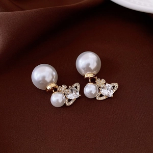 Detail view of gold heart orb earring with cubic zirconia and double-sided pearls