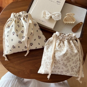 Detail of floral cotton drawstring pouches with rustic prints on a wooden table