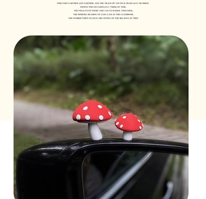 Close-up of two red mushroom car ornaments mounted on a side mirror with nature background