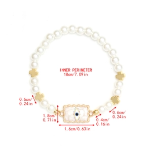 Macro view of beaded bracelet with pearl beads, gold crosses and blue evil eye charm