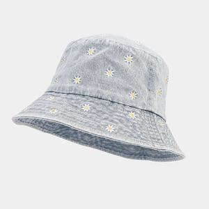 Detailed embroidery of white daisy flowers on light blue denim fabric bucket hat