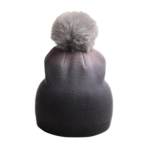 Detailansicht einer winterlichen Strickmütze mit coolem Farbverlauf und grauem Bommel