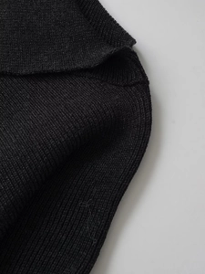 Close-up of black wool knit poncho with vertical texture and soft ribbed fabric detail