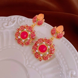 Vue macro de boucles d'oreilles en émail rouge avec perles et cristaux sur céramique