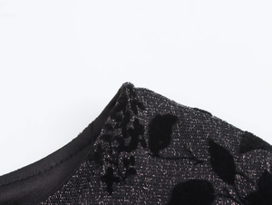 Close-up of black jacquard knit fabric with metallic yarn and flocking texture details