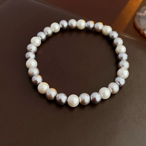 Detail view of white and grey pearls on a luxury necklace with a textured dark background