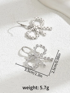 Detail view of silver bow earrings with zircon stones and dimensions 3.5cm by 2.5cm