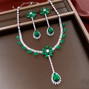 Détail d'une parure de luxe avec collier et boucles d'oreilles fleur émeraude et zircon