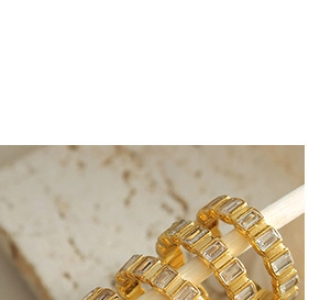 Detailed close-up of golden eternity rings featuring rectangular zircon stones on a display