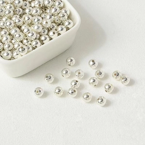 Polished silver metal spacer beads for jewelry making in a white ceramic bowl