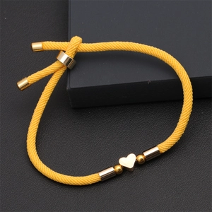 Detail view of yellow braided cord bracelet with adjustable slide knot and gold heart charm