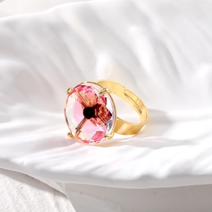 Adjustable gold ring with a large faceted pink crystal on elegant white fabric background