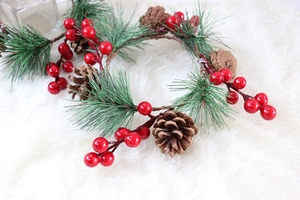 Detailaufnahme von PVC-Tannennadeln, roten Beeren und Zapfen auf einem Adventskranz