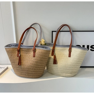 Detail of woven straw tote bags with fringe tassels and brown PU leather handles