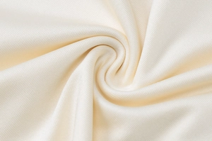 Makroaufnahme der beigen Strickstofftextur mit feinen Details und Gewebe des Kleidungsstücks