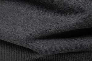 Detailed macro view of dark grey knit fabric texture with ribbed hem on men's sweater