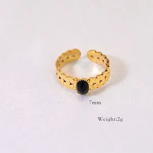 Detail of bohemian gold ring with black oval gemstone and hollow leaf pattern texture