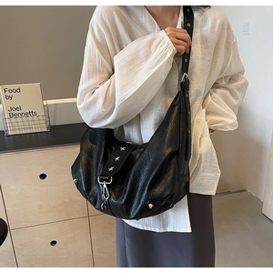Detail of black soft leather hobo bag featuring silver star studs and metal lobster clasp