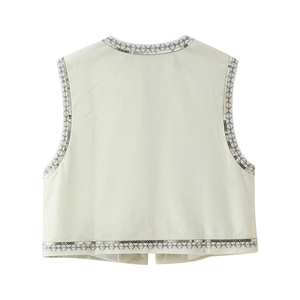 Detailed view of white velvet vest featuring silver sequins and geometric embroidery