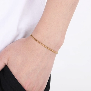 Detailed close-up of a delicate gold stainless steel chain worn on a model's wrist