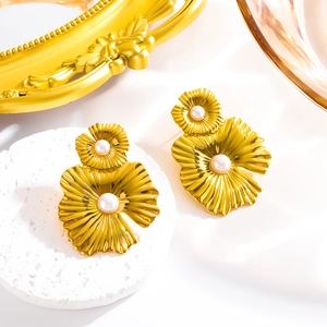 Elegant gold flower leaf earrings with pearls on a natural stone display stand