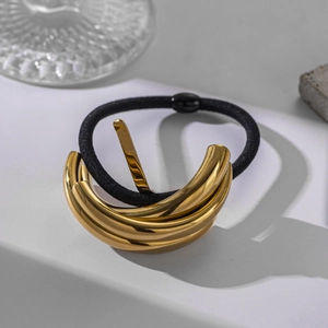 Detail of high-gloss gold layered metal buckle on black elastic hair tie for ponytails